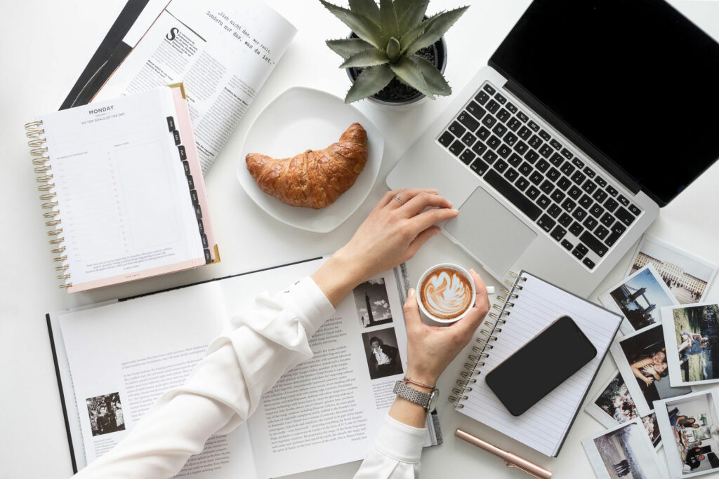 Schreibtisch mit Fotos, Pflanze, Croissant & Kaffee